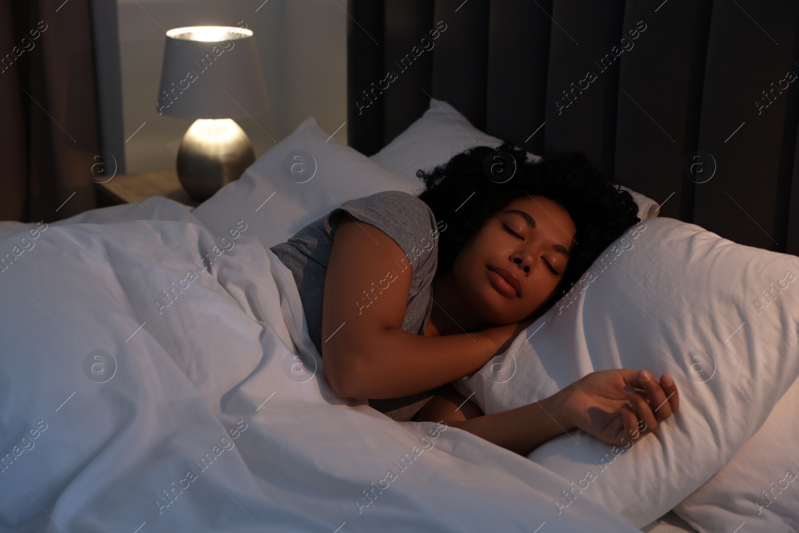 Photo of Young woman sleeping in soft bed at night