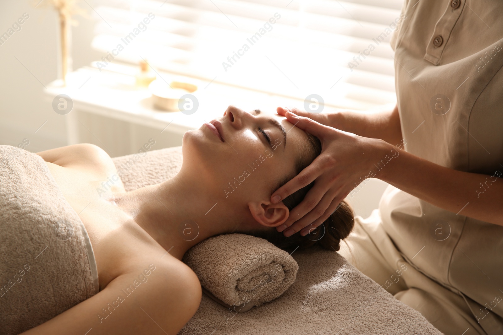 Photo of Young woman receiving head massage in spa salon