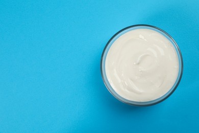 Photo of Bowl of tasty organic yogurt on light blue background