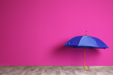 Photo of Beautiful open umbrella on floor near color wall with space for design