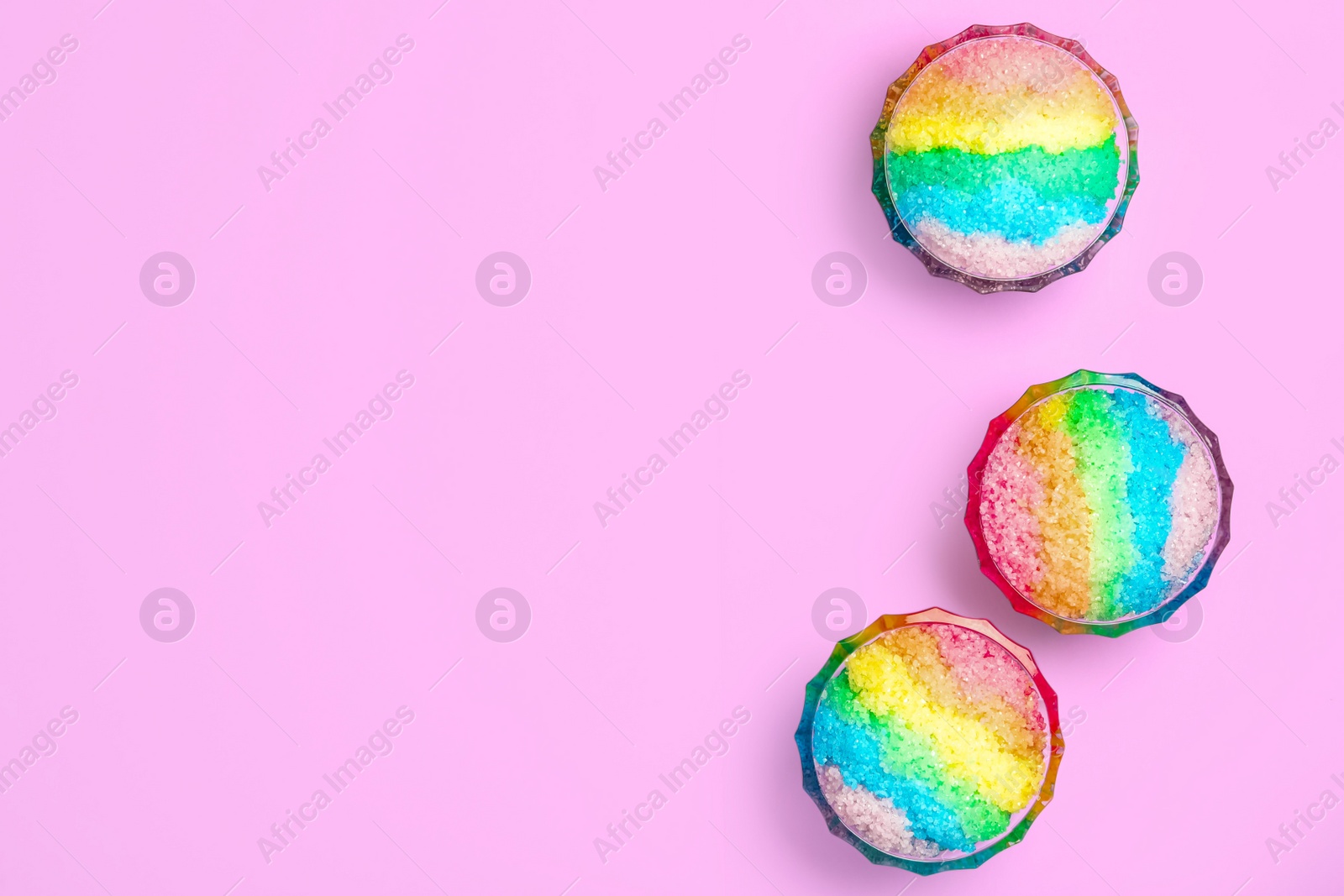 Photo of Rainbow shaving ice in glass dessert bowls on lilac background, flat lay. Space for text