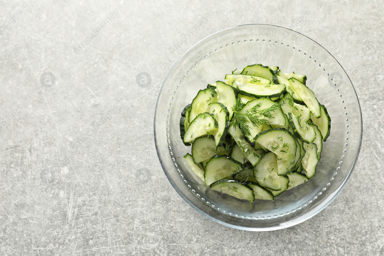 Photo of Delicious cucumber salad with dill in bowl on grey background, top view. Space for text