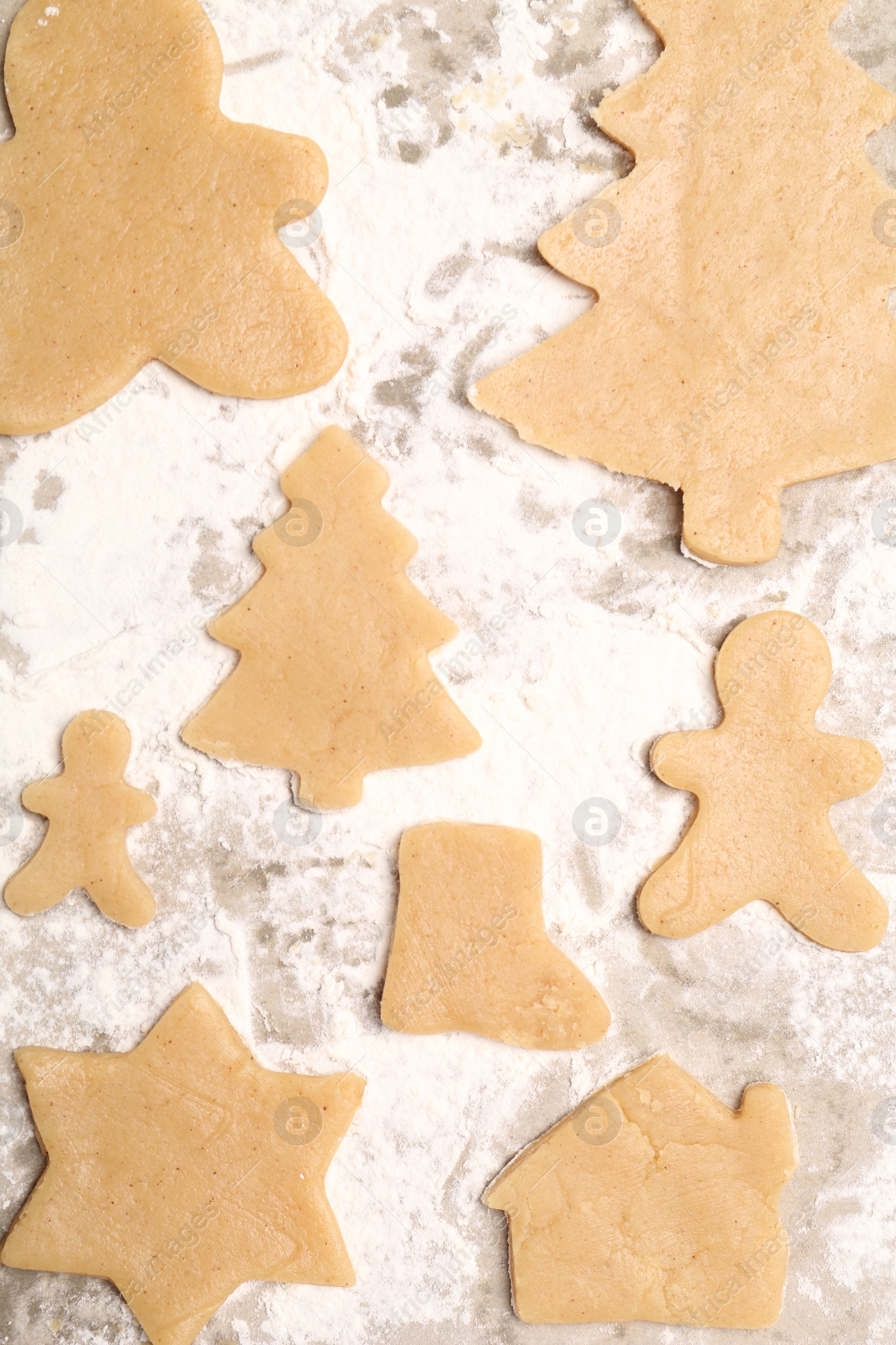 Photo of Raw Christmas cookies in different shapes on parchment paper, flat lay