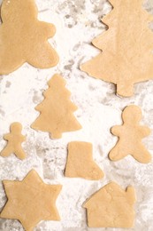 Photo of Raw Christmas cookies in different shapes on parchment paper, flat lay