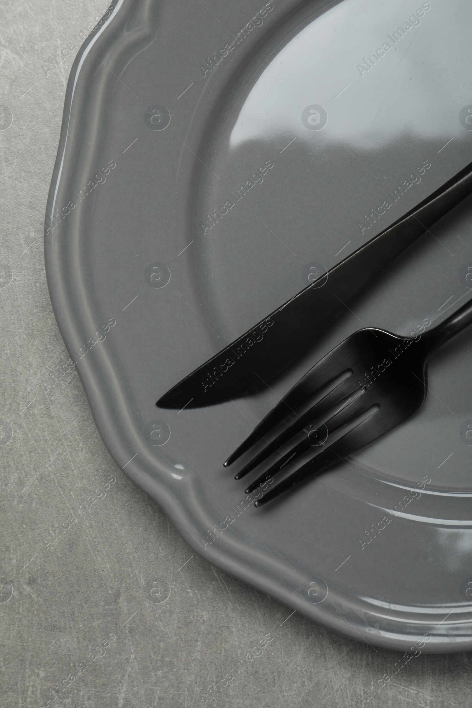 Photo of Stylish cutlery and plate on grey table, top view