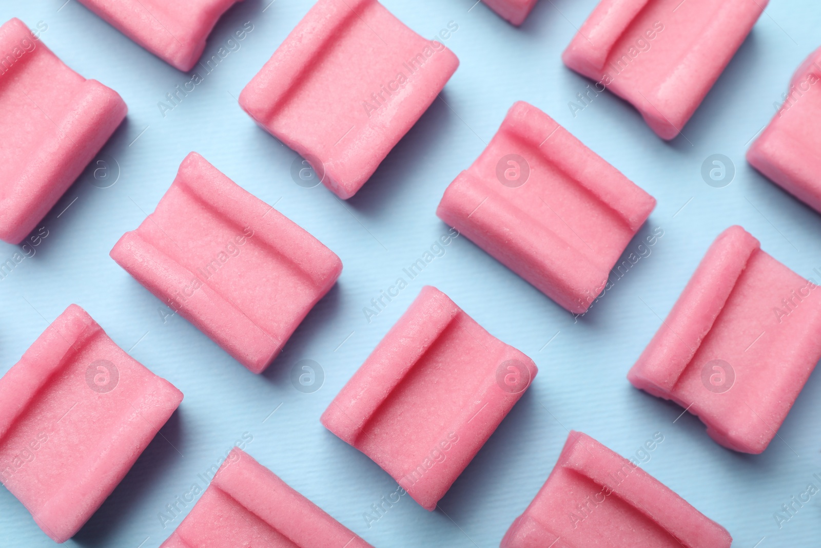 Photo of Tasty pink chewing gums on light blue background, flat lay