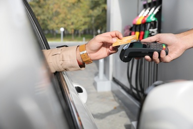 Man sitting in car and paying with credit card at gas station, closeup