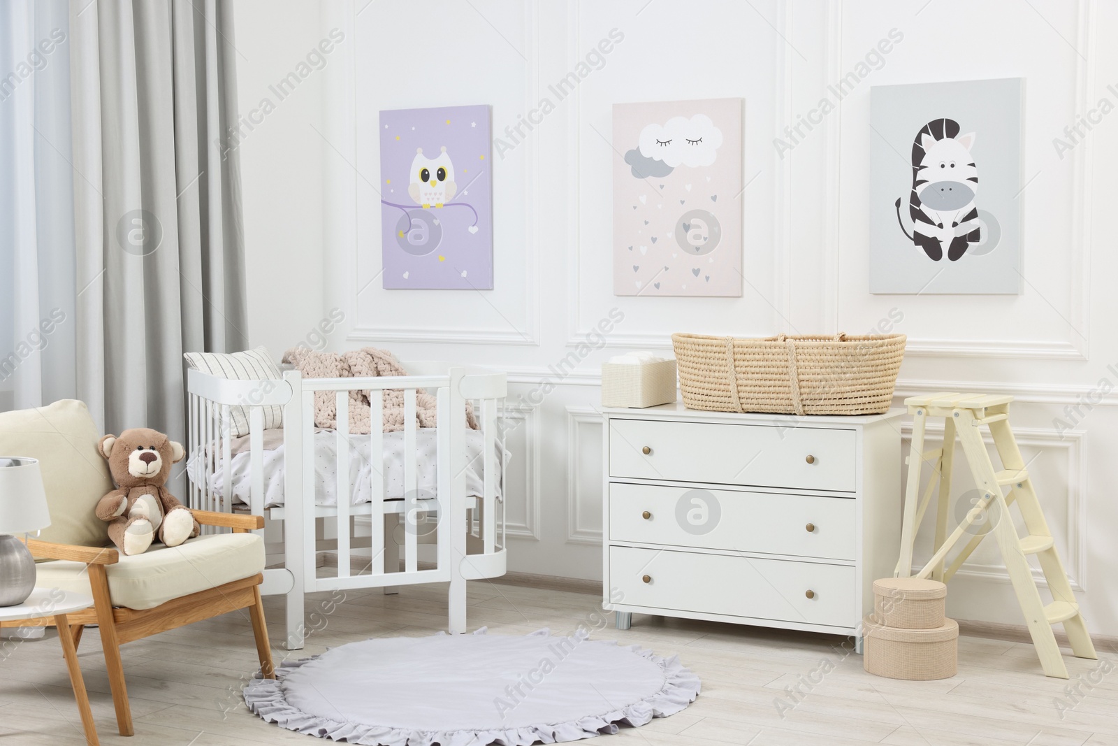 Photo of Newborn baby room interior with stylish furniture, comfortable crib and pictures of on wall