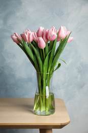 Photo of Beautiful pink spring tulips in vase on wooden table