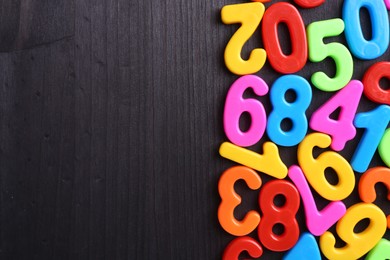 Photo of Colorful numbers on dark wooden school desk, flat lay. Space for text