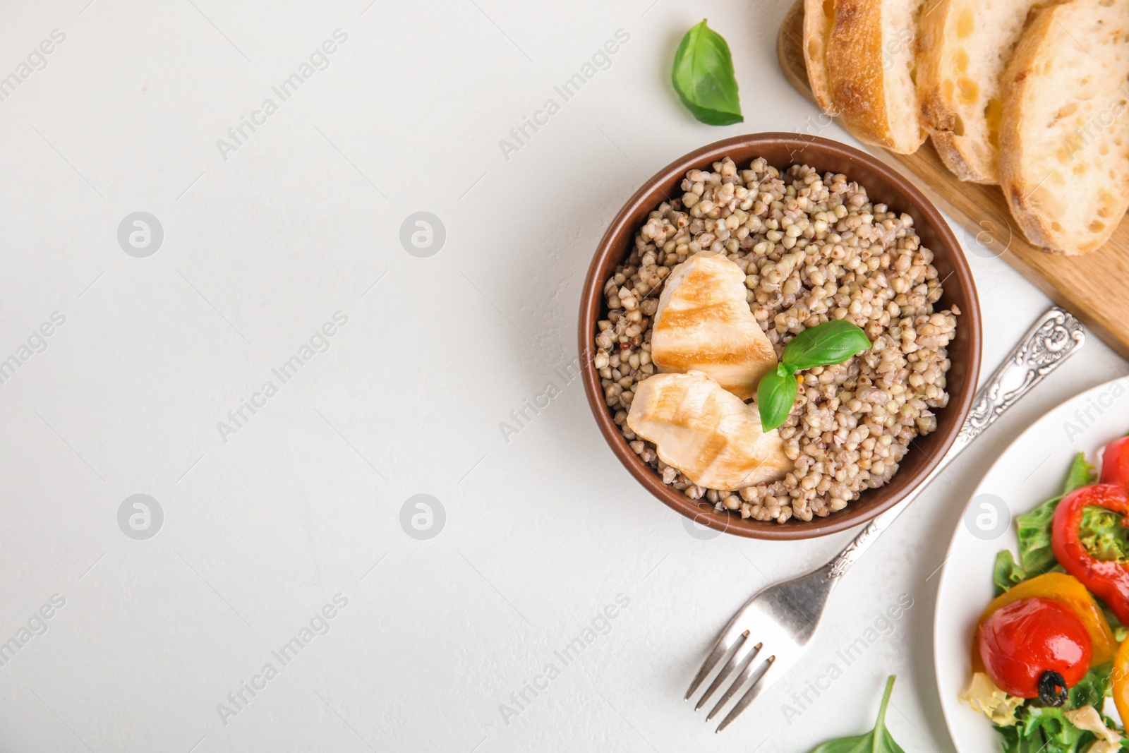 Photo of Tasty buckwheat porridge with meat on white table, flat lay. Space for text