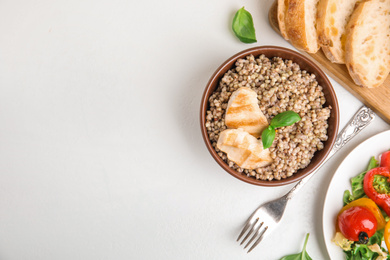 Photo of Tasty buckwheat porridge with meat on white table, flat lay. Space for text