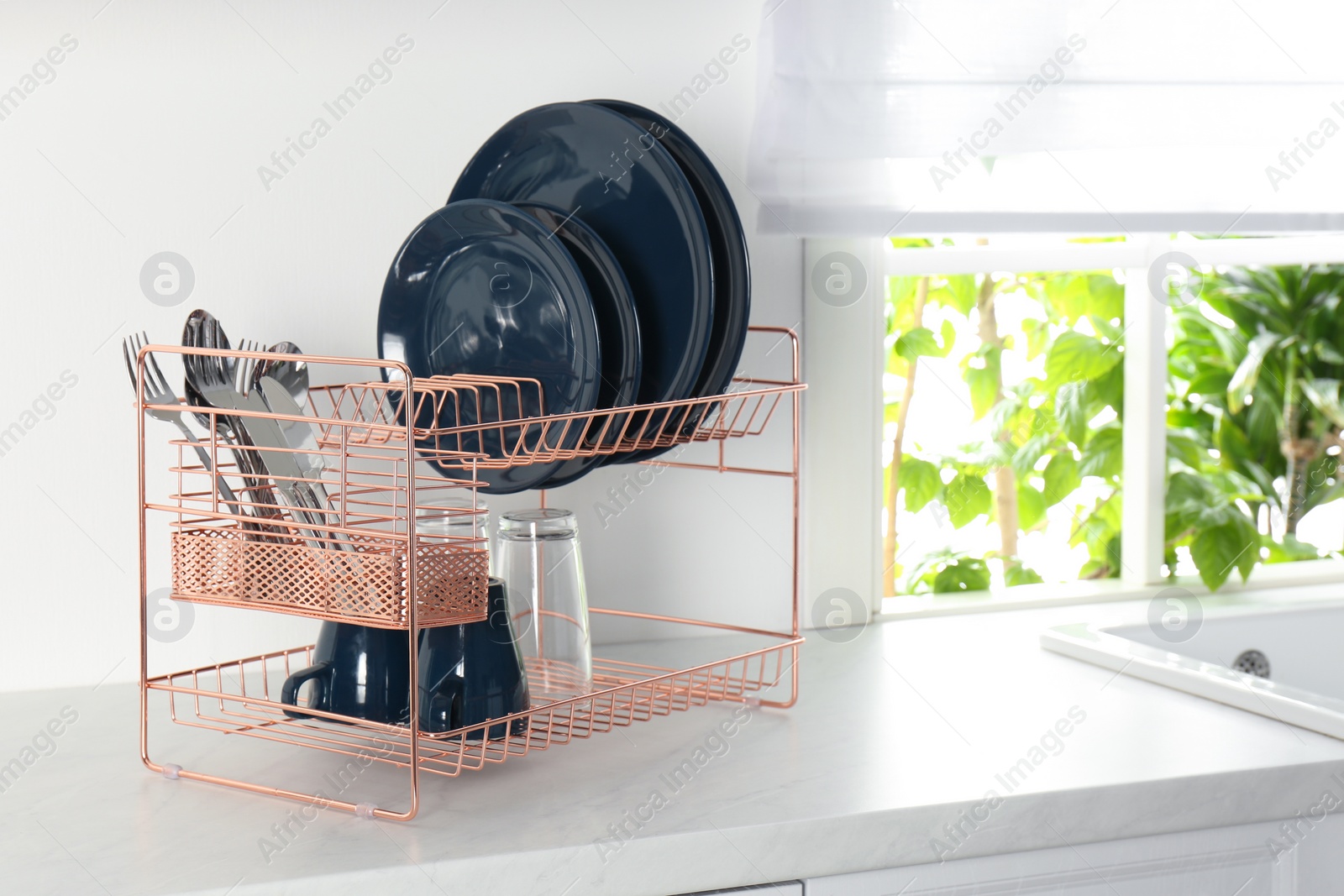 Photo of Drying rack with clean dishes on countertop in kitchen. Space for text