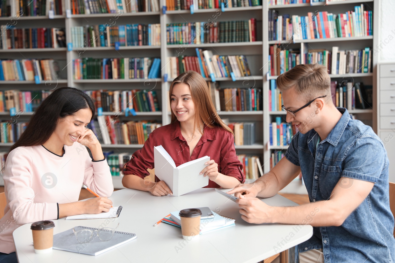 Photo of Young people discussing group project at table in library