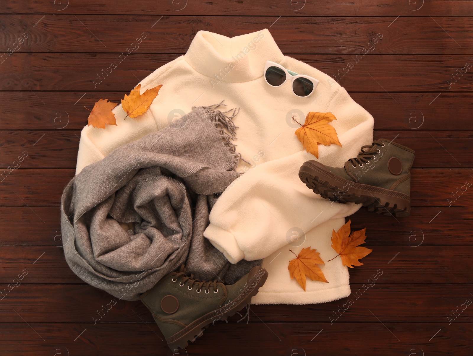 Photo of Flat lay composition with sweater and dry leaves on brown wooden background. Autumn season