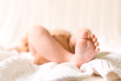 Photo of Cute newborn baby lying on white knitted plaid, closeup of legs. Space for text