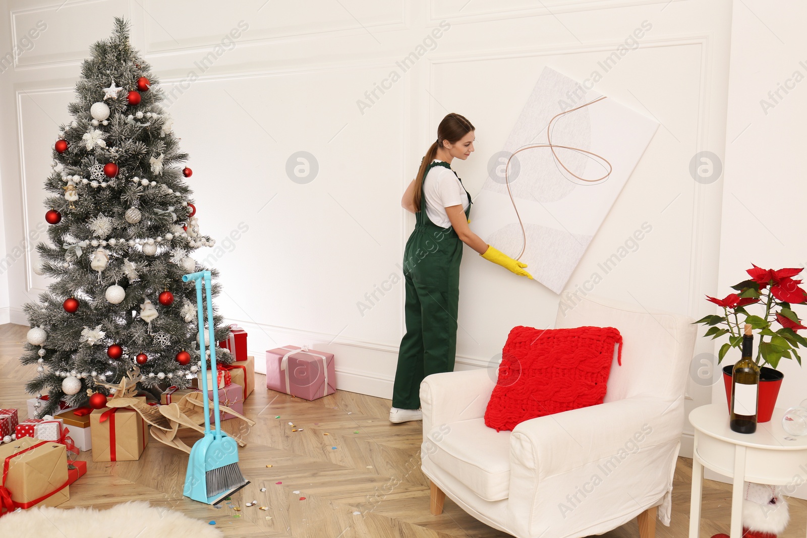 Photo of Woman from cleaning service working in messy room after New Year party