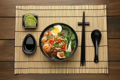 Delicious ramen with shrimps and egg in bowl served on wooden table, flat lay