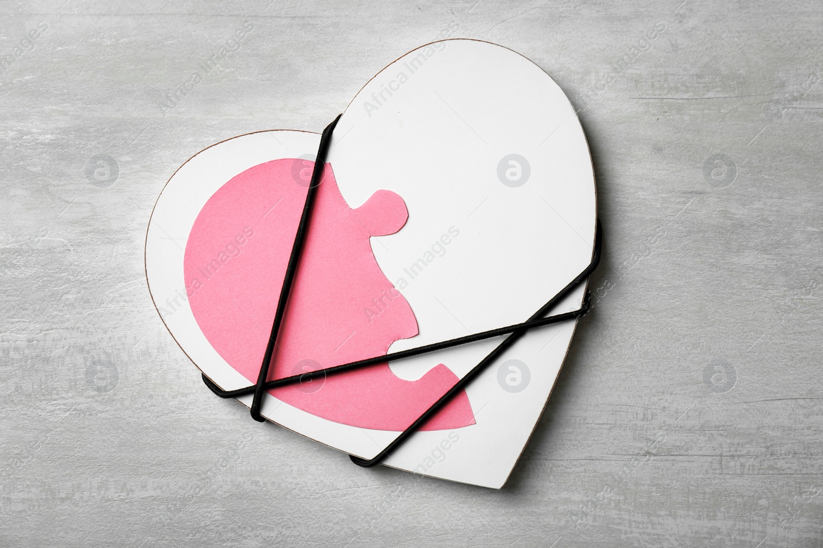 Photo of Half of paper heart tied with cord to detail on gray background, top view. Relationship problems