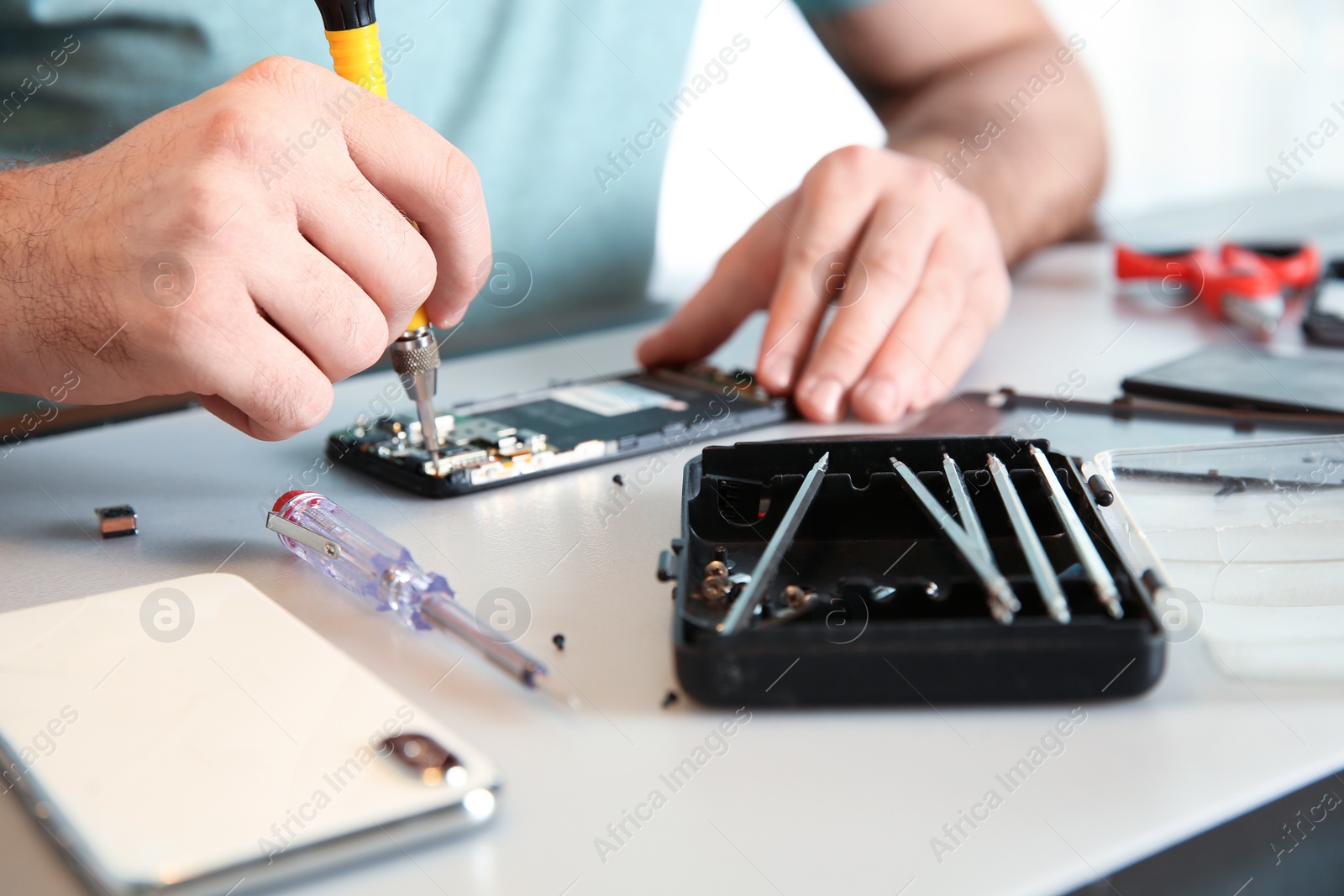 Photo of Technician repairing mobile phone at table, closeup