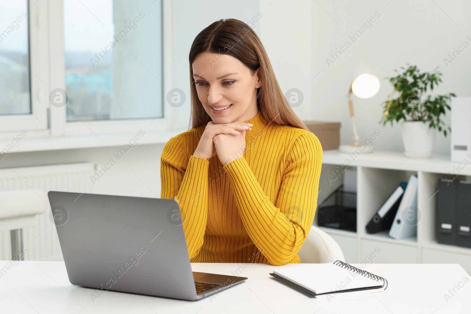 Photo of Woman having video chat via laptop at table in office