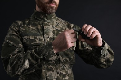 Photo of Soldier pulling safety pin out of hand grenade on black background, closeup. Military service