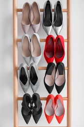 Photo of Rack with high heeled shoes on light background