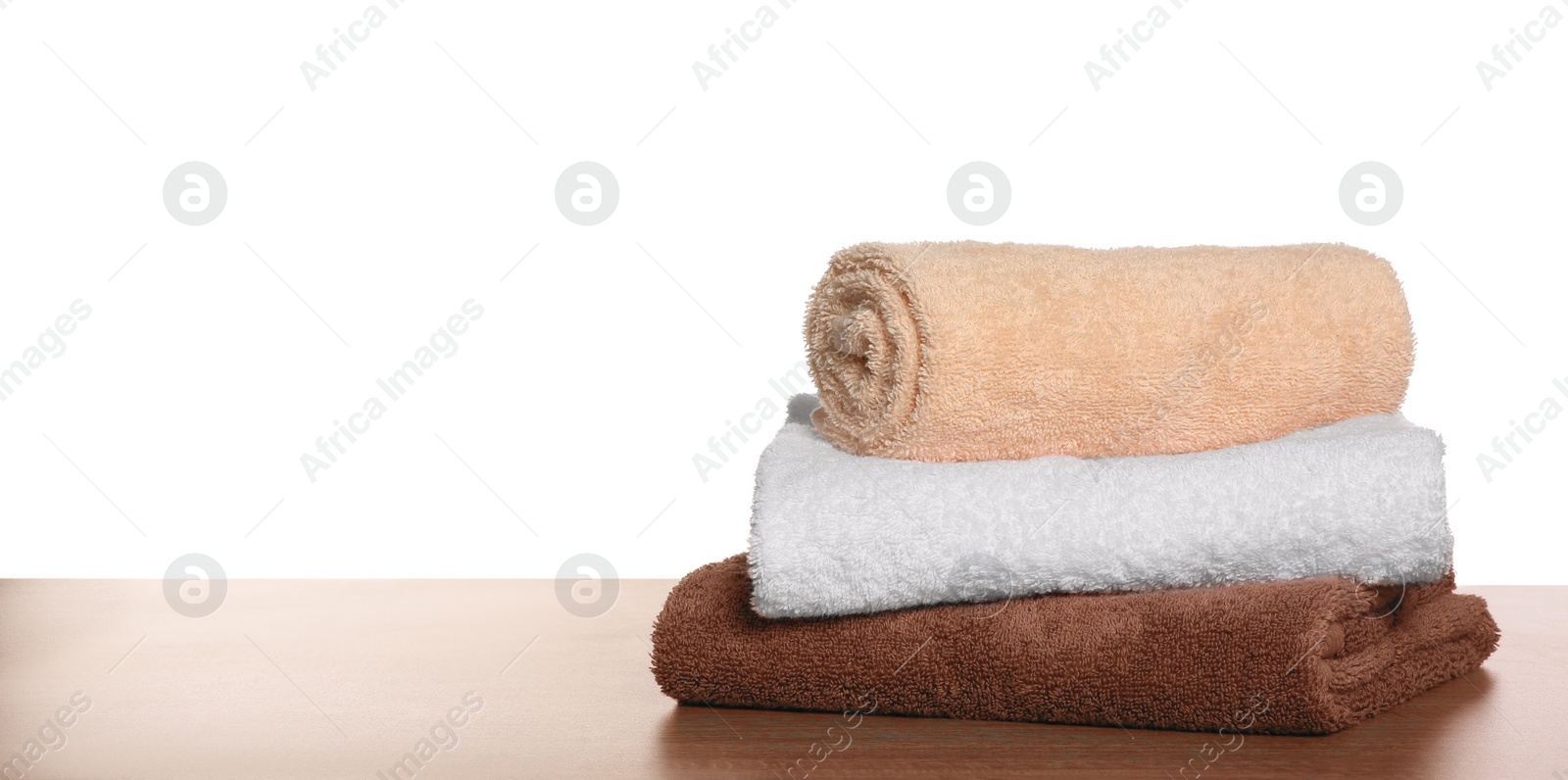 Photo of Soft colorful terry towels on wooden table against white background, space for text