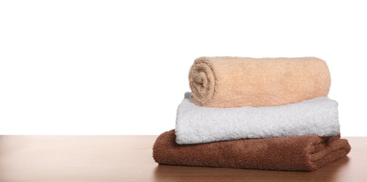 Soft colorful terry towels on wooden table against white background, space for text