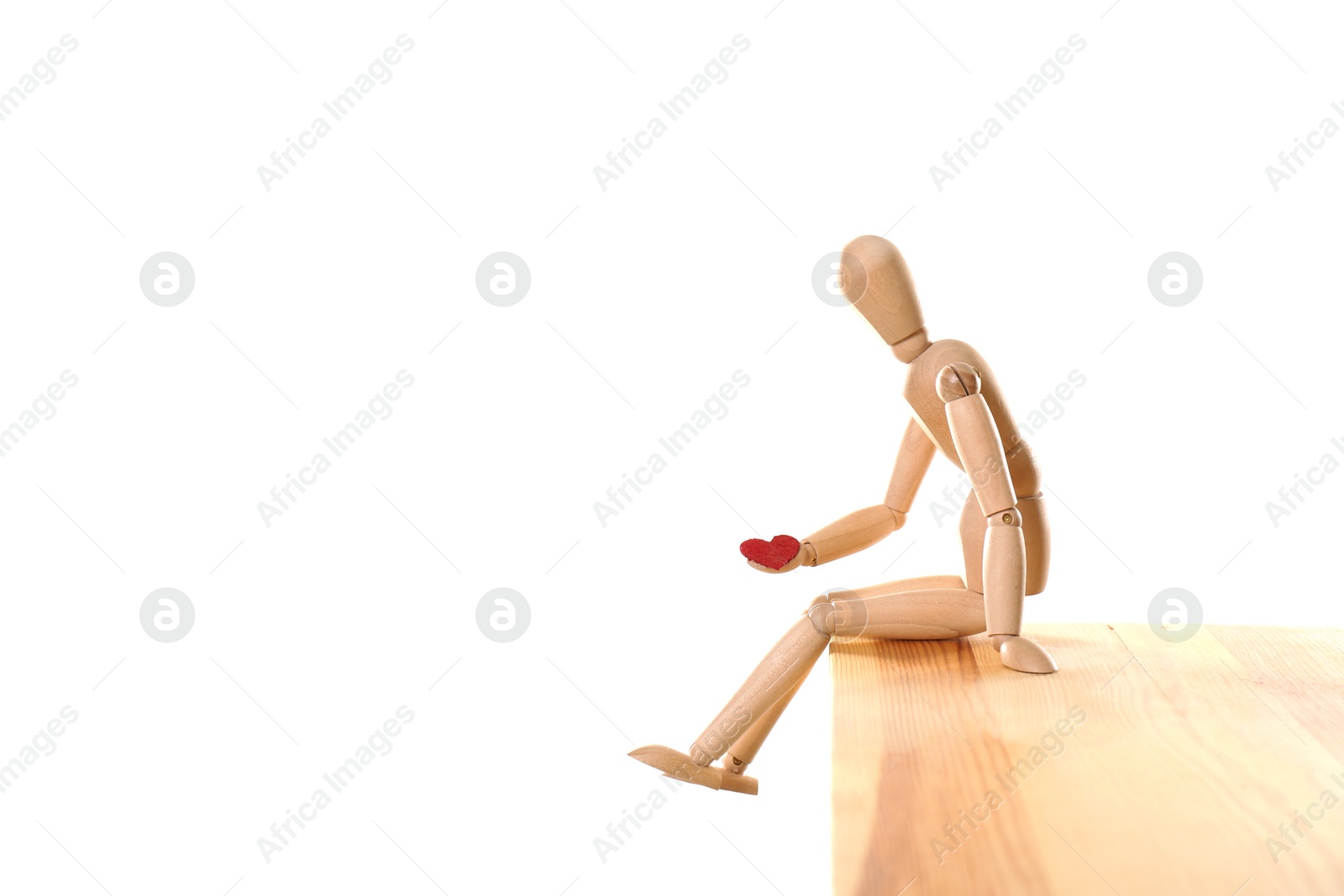 Photo of Wooden puppet with small heart sitting on table against white background. Relationship problems