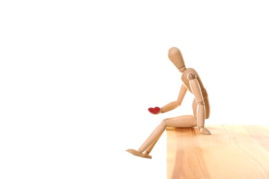 Photo of Wooden puppet with small heart sitting on table against white background. Relationship problems