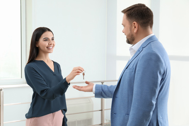 Photo of Real estate agent giving key to client in new apartment