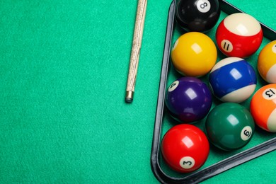 Set of billiard balls with rack and cue on green table, flat lay. Space for text