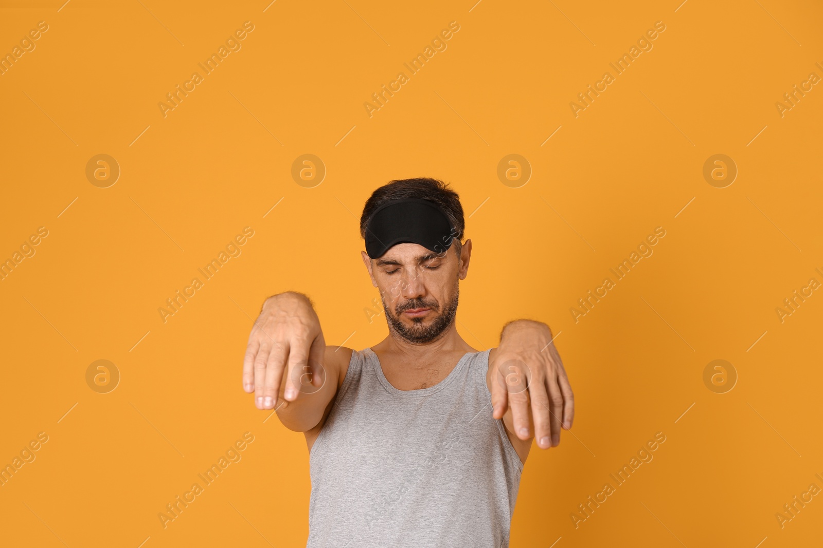 Photo of Man with eye mask in sleepwalking state on yellow background