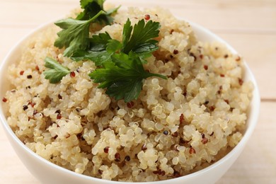 Photo of Tasty quinoa porridge with parsley in bowl on table, closeup