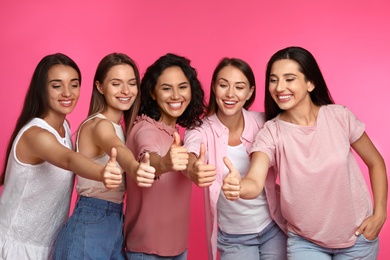 Photo of Happy women showing thumbs up on pink background. Girl power concept