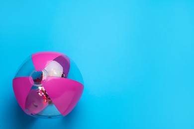 Photo of Bright beach ball on light blue background, top view. Space for text