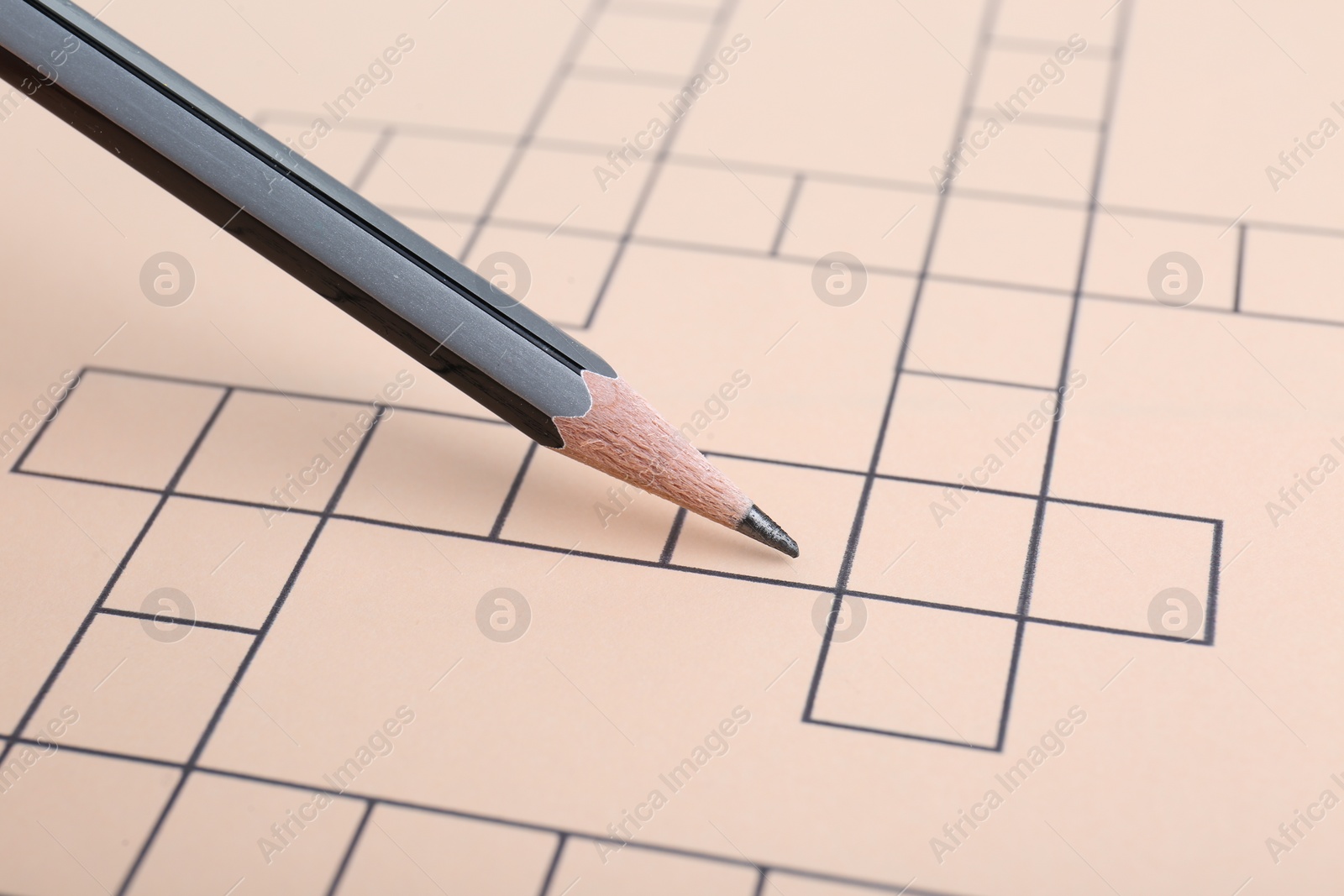 Photo of Pencil and blank crossword, closeup. Space for text