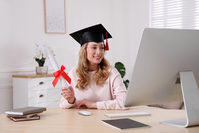 Photo of Happy student with graduation hat and diploma at workplace in office