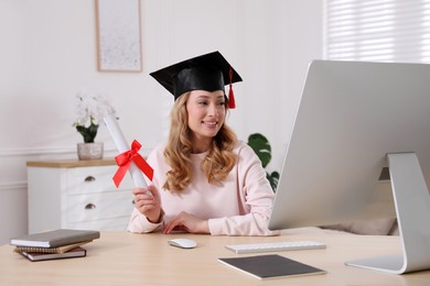 Happy student with graduation hat and diploma at workplace in office