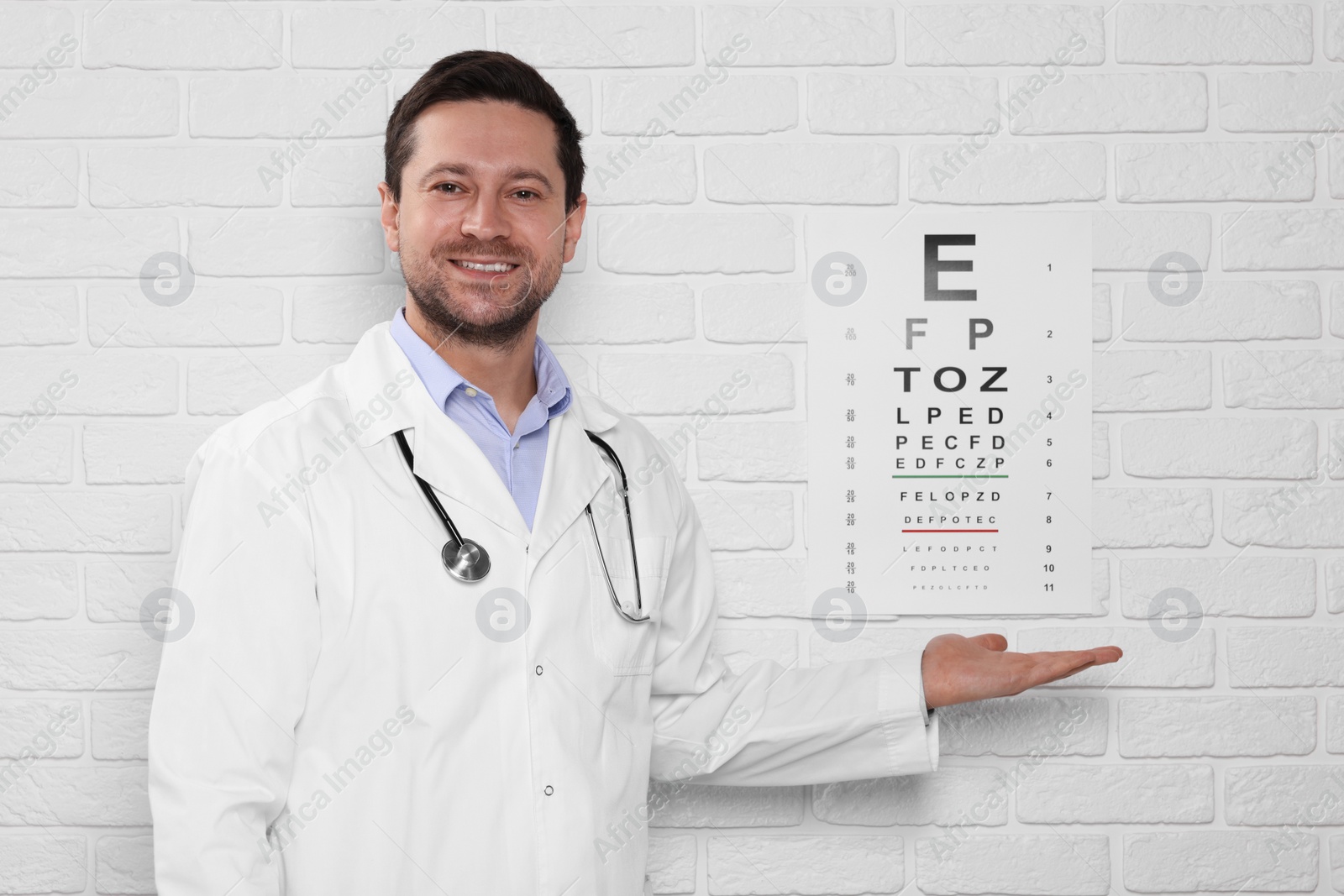 Photo of Ophthalmologist showing vision test chart on white brick wall
