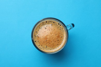 Photo of Fresh coffee in cup on light blue background, top view