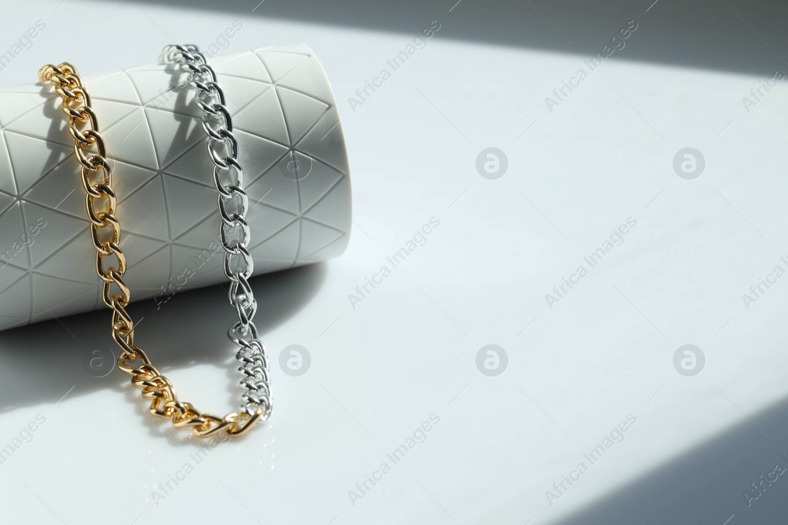 Photo of Metal chain on white table, space for text. Luxury jewelry