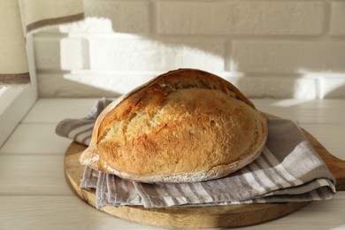 Photo of Freshly baked sourdough bread on white wooden table indoors