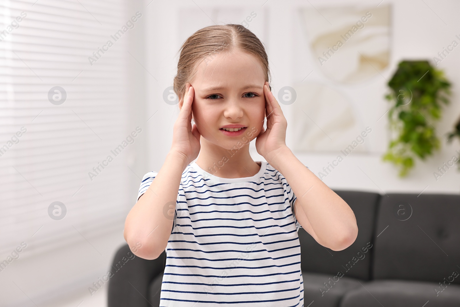 Photo of Little girl suffering from headache at home