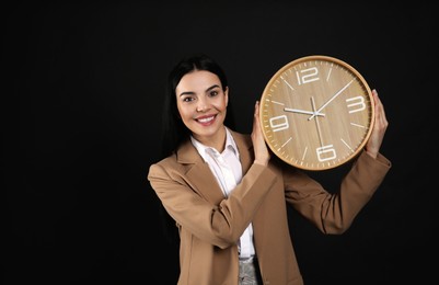 Photo of Businesswoman holding clock on black background. Time management