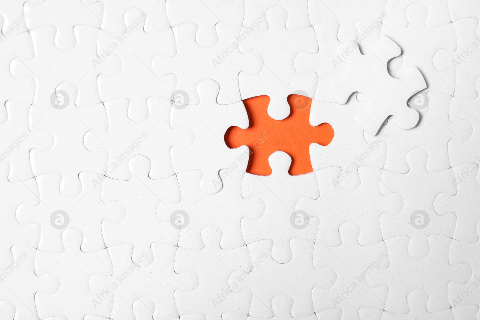 Photo of Blank white puzzle with separated piece on orange background, top view