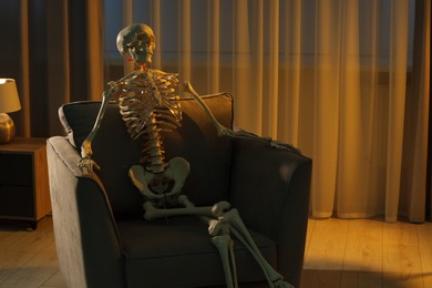 Waiting concept. Human skeleton sitting in armchair indoors