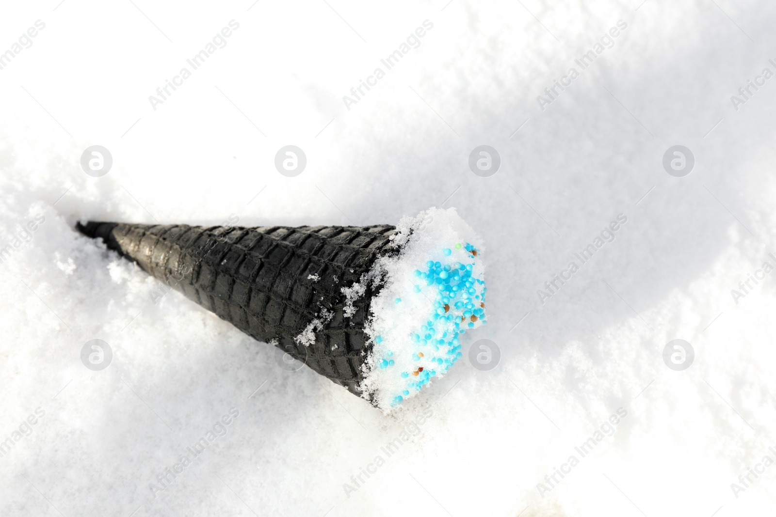 Photo of Waffle cone with ice cream on snow, space for text