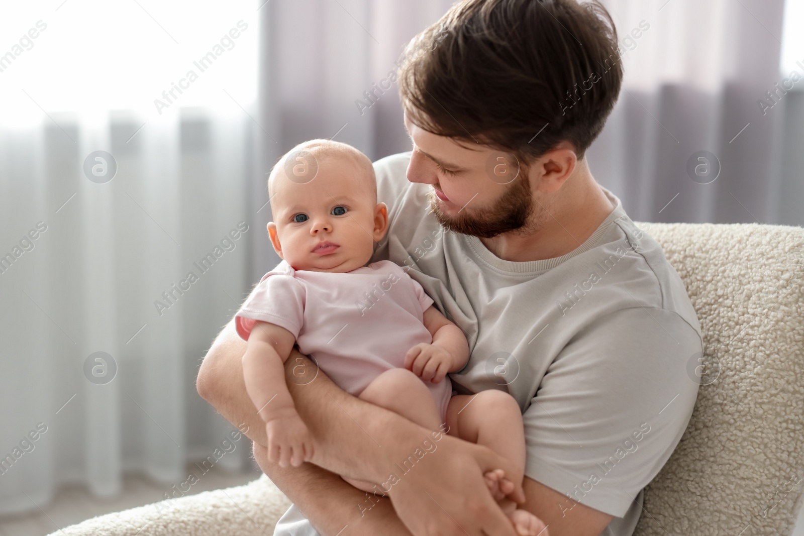 Photo of Father with his cute baby in armchair at home, space for text